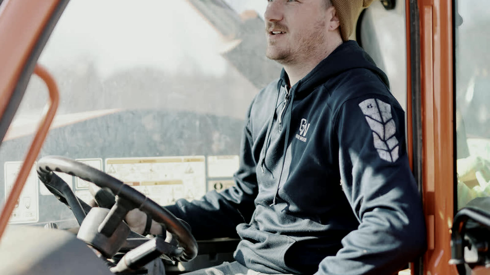A crew member at the controls of a telehandler on a job site